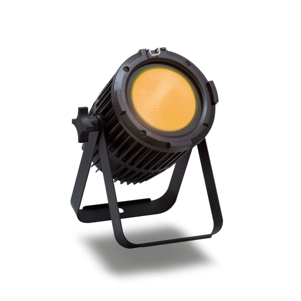 A black stage spotlight with a yellow lens, mounted on an adjustable stand, showcases professional lighting for audio or video setups, facing slightly upward against a white background.