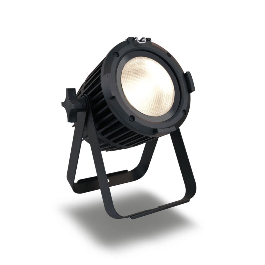 A black, cylindrical stage spotlight with a sturdy metal stand is angled upward. The lighting fixture is on, emitting a soft, bright glow. The background is plain white.