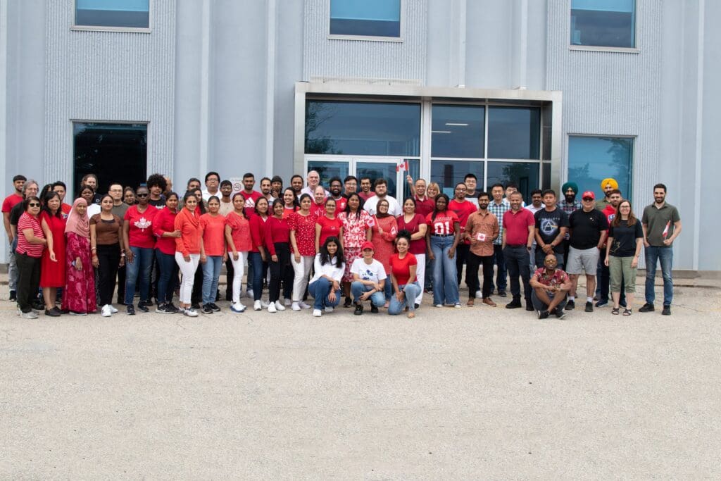 A group of AC Americas employees pose in red shirts for Canada Day